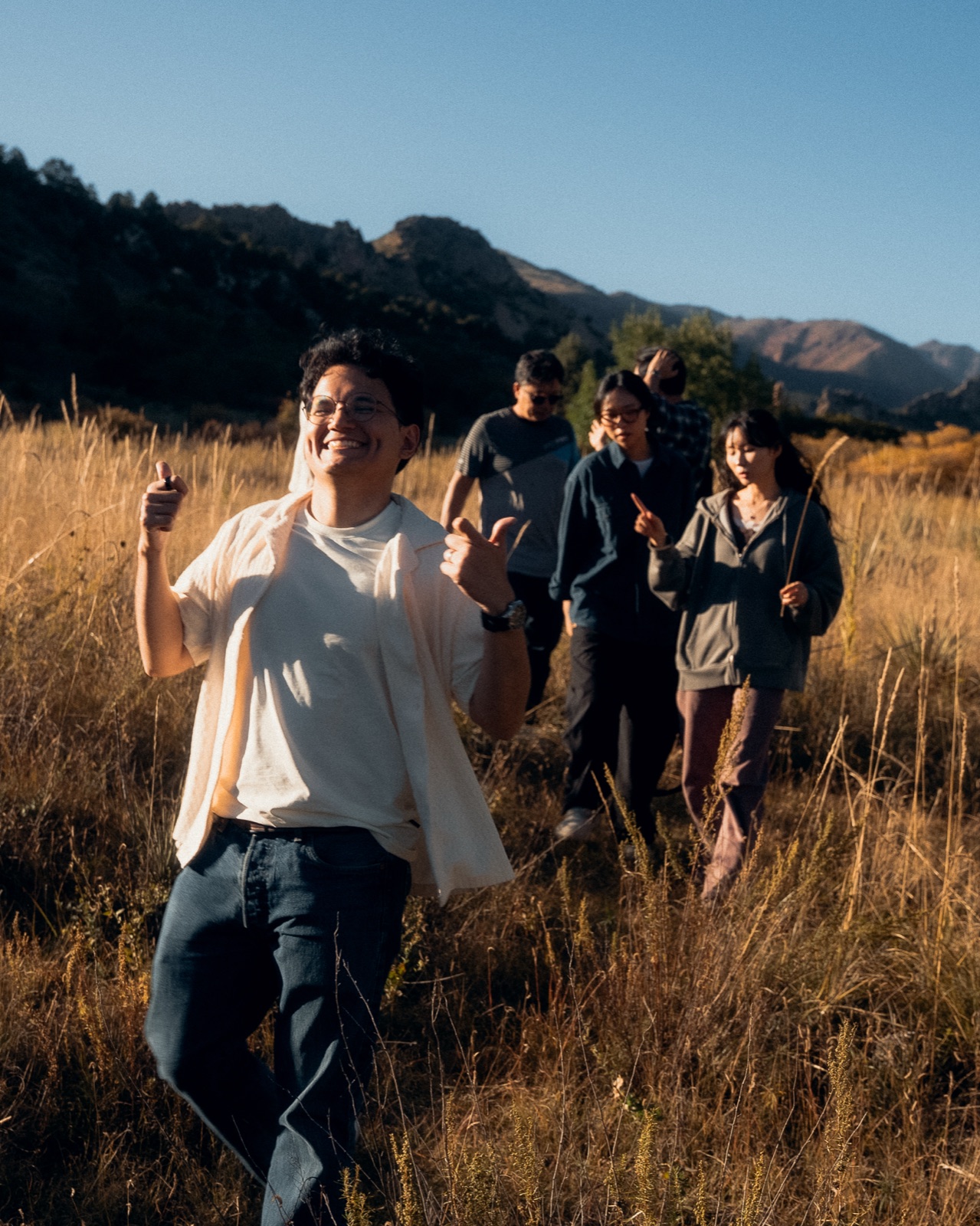 Students walking together through a golden field toward the mountains — the invitation to join YWAM Château