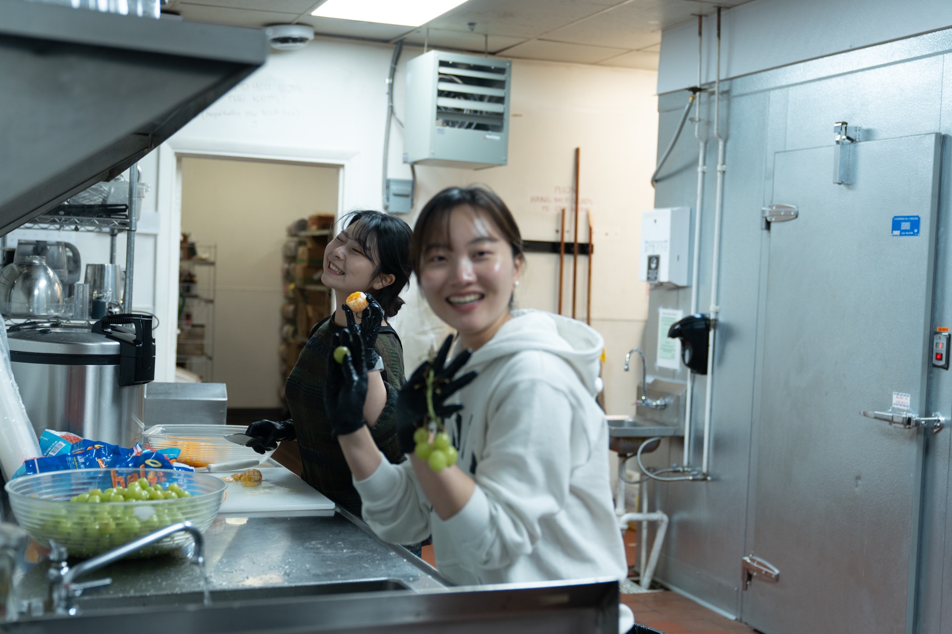 Two SPL students laughing together while preparing food in the YWAM kitchen